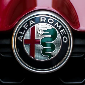 Badge Alfa Romeo photographié sur la calandre d'une voiture rouge