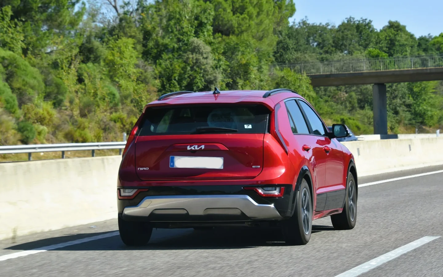 Kia Niro Hybrid rouge de deuxième génération vu de trois quarts arrière sur route