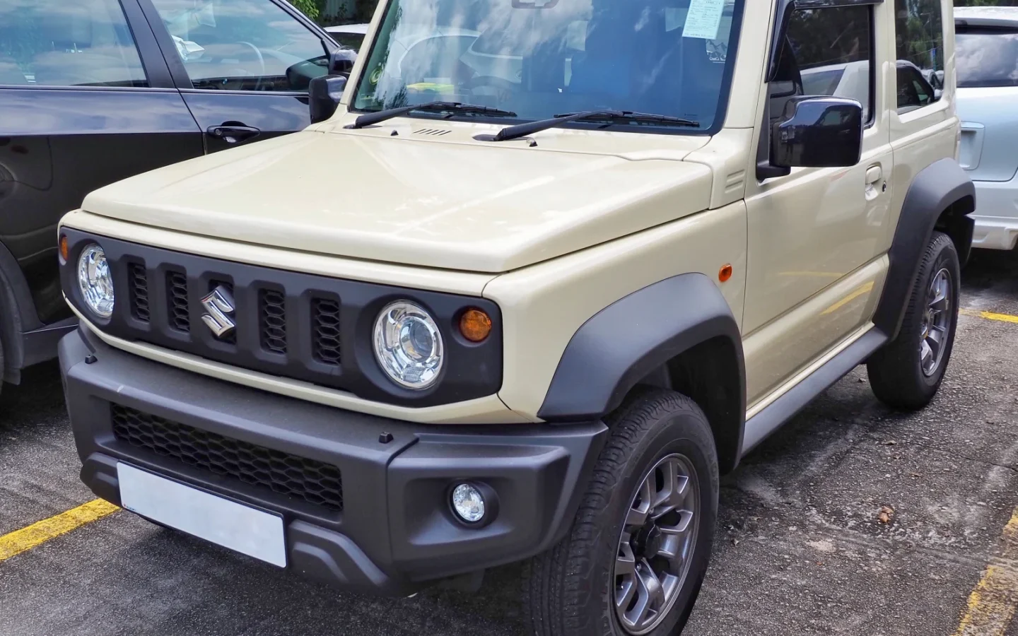 Suzuki Jimny JB74 beige vu de trois quarts avant ; configuration étrangère non contractuelle