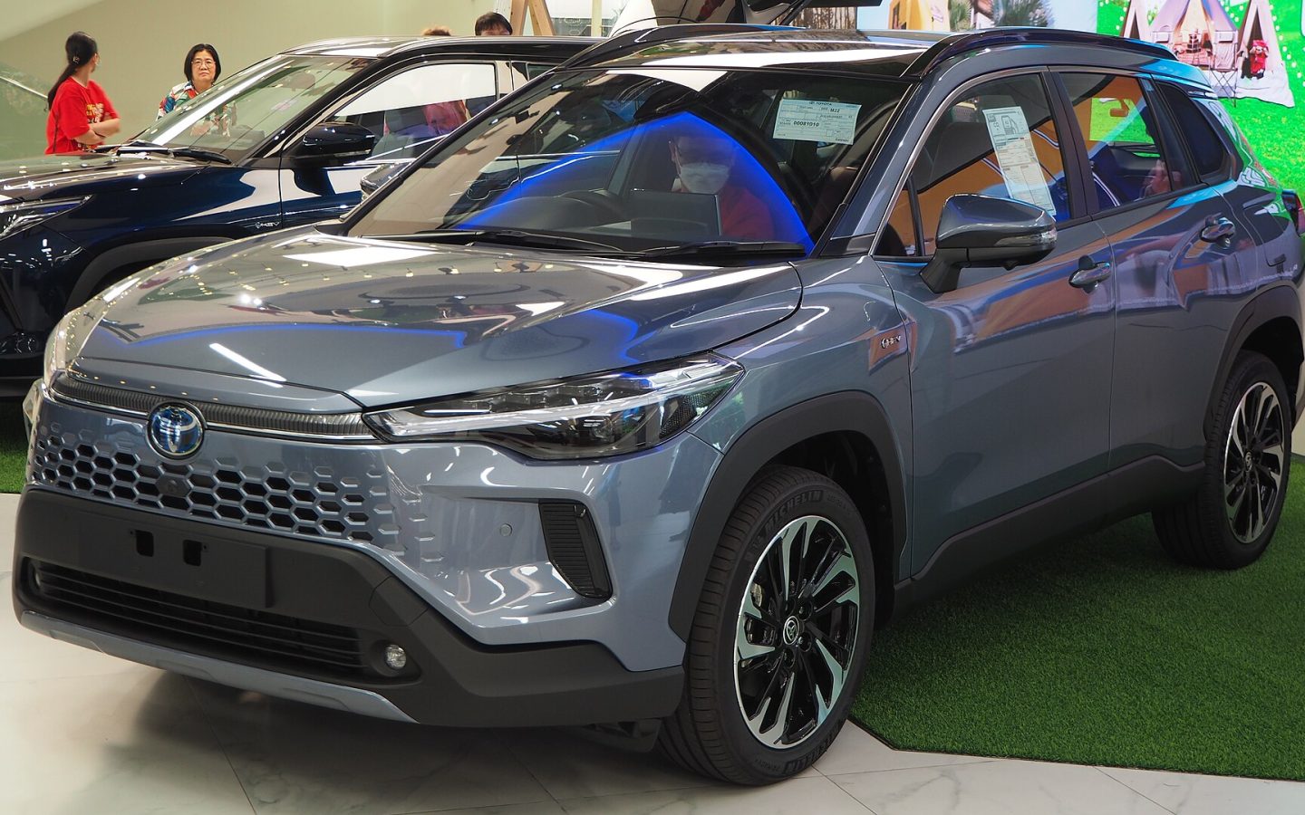 Toyota Corolla Cross restylé bleu-gris, vue de trois quarts avant en showroom ; illustration thaïlandaise non contractuelle